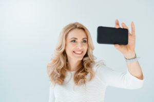 woman taking selfie showing off new smile.